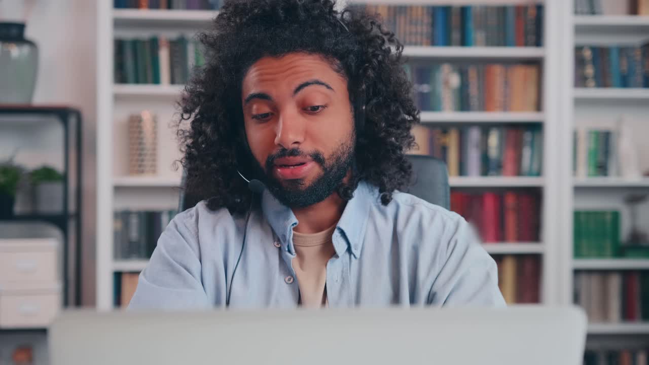 Hooked arabian man talks by video call with wired headset takes online exam