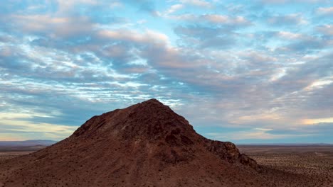 Dynamic-orbiting-aerial-hyper-lapse-of-a-lone-butte-in-the-Mojave-Desert-during-a-colorful-sunset