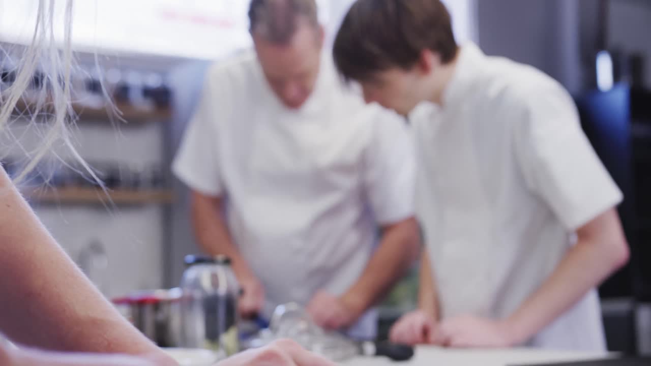 cocinero profesional caucásico vestido con ropa blanca en una cocina de un restaurante enseñando