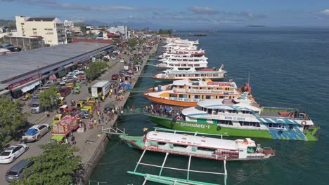 Passenger-boats-docked-at-the-seaport-while-unloading-travelers,-aerial-slow-motion-static