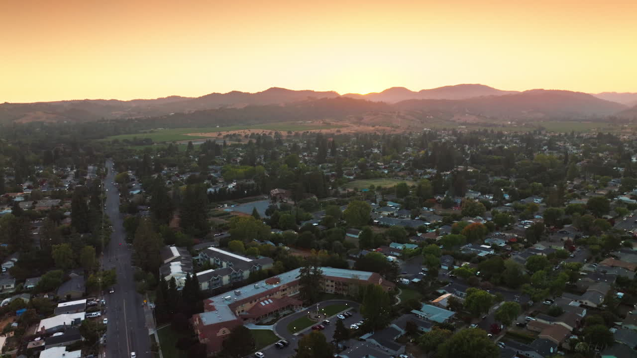 Flying over green city of Napa, California, USA. Mountainous skyline at backdrop of pink skies. Aerial view.