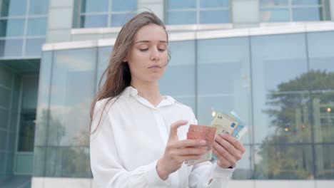 baltic blonde businesswoman: counting euros outdoors