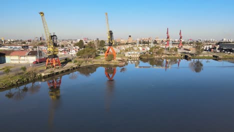 backward aerial of tall port cranes by still water in buenos aires