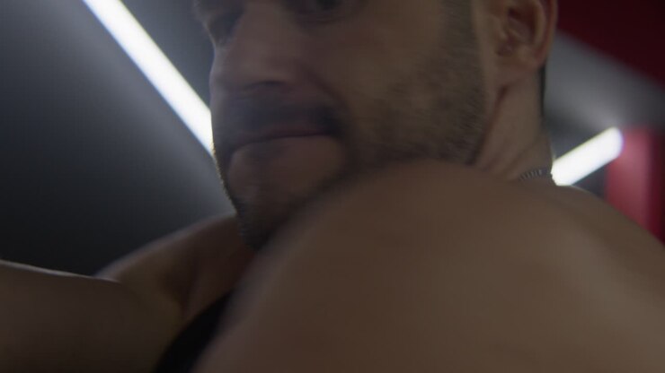 Un uomo che allunga le spalle riscaldandosi prima dell'allenamento, primo piano.