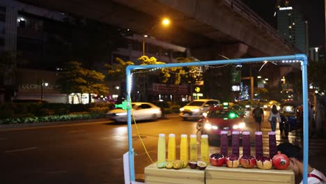 exhibición de velas coloridas en una calle de noche ocupada