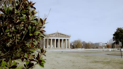 The-Partehnon-building-in-Nashville,-Tennessee-wide-shot-with-magnolia-tree-in-foreground-with-video-tilting-down