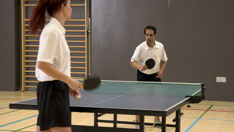 playing table tennis, man hitting ball with paddle in indoor sports hall