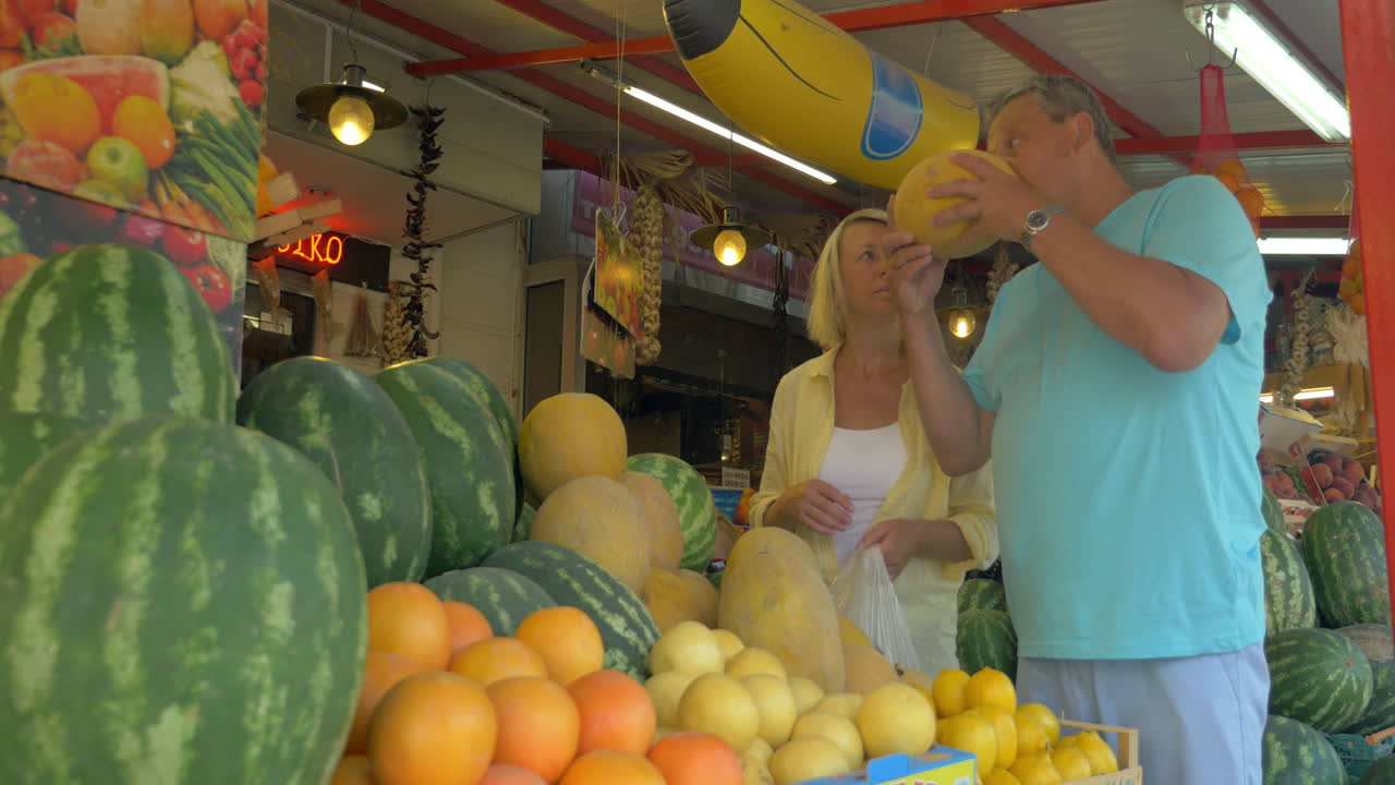 hombre y mujer eligiendo melón en el mercado