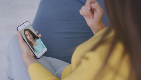 Mujer-Joven-Chateando-Por-Video-Con-Un-Amigo-Usando-Un-Teléfono-Inteligente-Saludando-Con-La-Mano-Compartiendo-Durante-El-Autoaislamiento-Mejores-Amigos-Disfrutando-De-La-Comunicación-A-Larga-Distancia