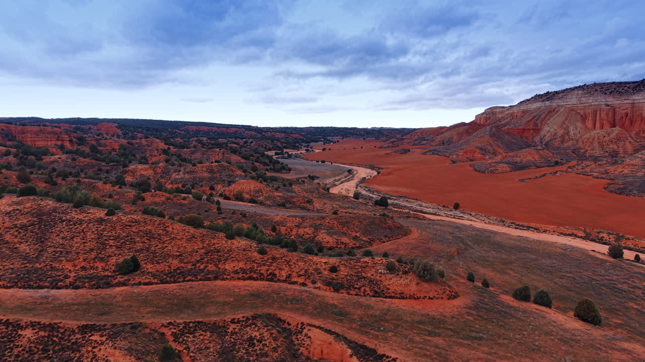 Breed panoramisch uitzicht op een rode kleivallei en droge rivier. Luchtfoto van rode badlands met een kronkelend zandpad en sedimentaire kliffen in Spanje