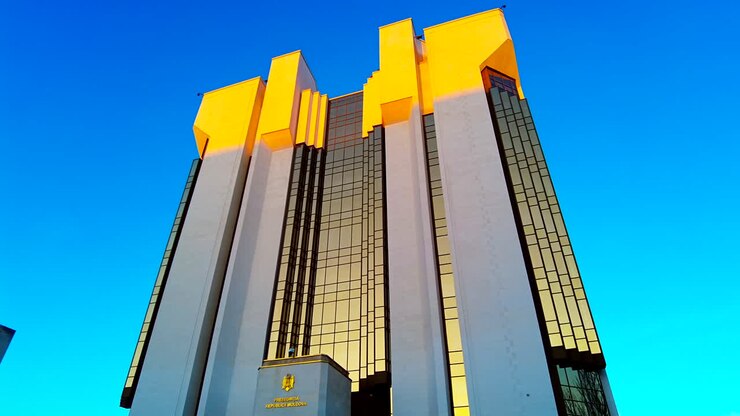 Sob um céu azul brilhante, um edifício impressionante com um telhado amarelo vibrante reflete a luz do sol. Ele exibe uma arquitetura moderna em um ambiente urbano animado, cativando os transeuntes.