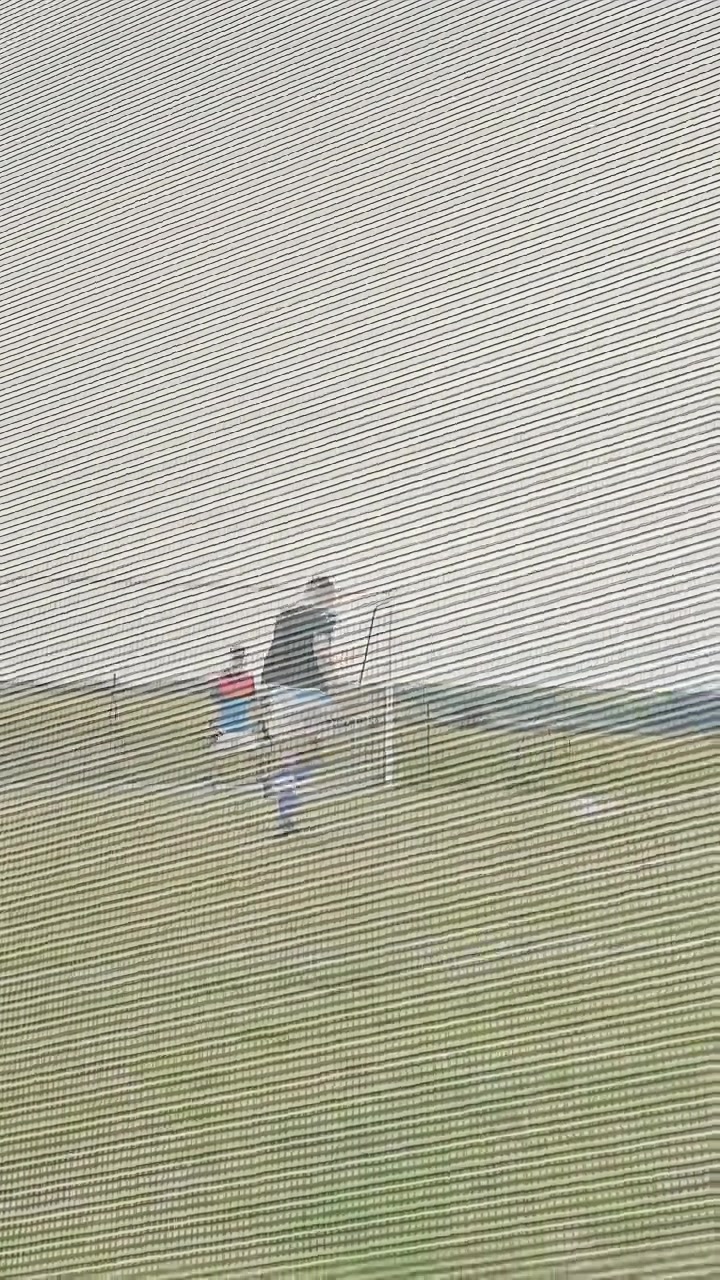Vertical video: Man walking from camera, leading teen and teammates toward soccer goal for practice