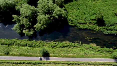 El-Río-Stour-4k-Imágenes-De-Drones-Con-Un-Automóvil-De-Movilidad-Conduciendo-A-Un-Lado