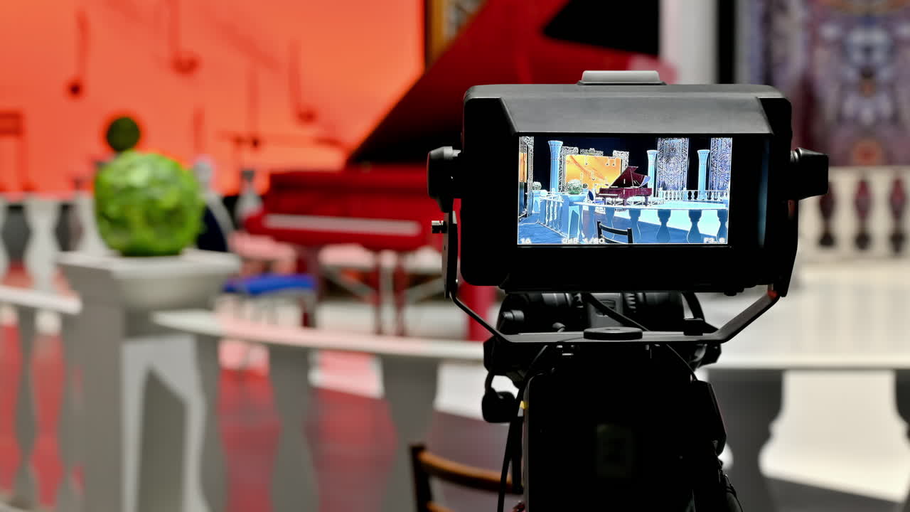 Professional camera filming a red piano on the backstage of a TV set