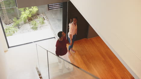 smiling african american man walking up stairs while african american woman stands in home entryway