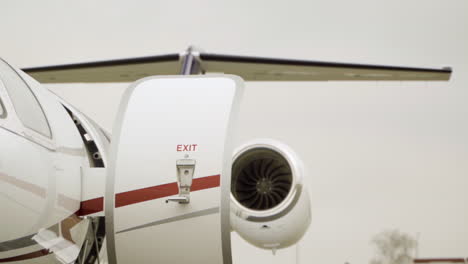 Panning-shot-of-luxury-cessna-aircraft-with-open-door-parking-at-airport-during-cloudy-day