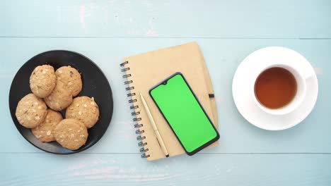 vista superior del teléfono inteligente, galletas y té en la mesa