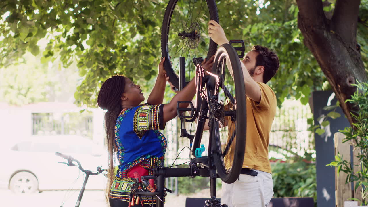 Multiethnic couple fastens bicycle wheel