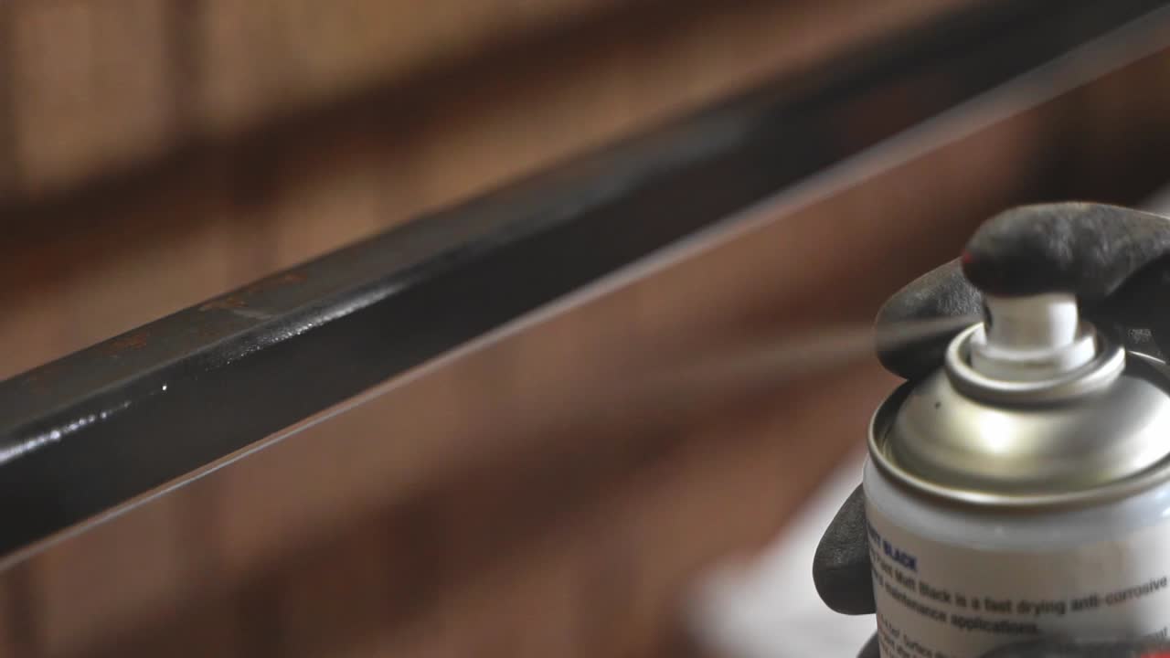 taller carpintero rociando pintura negra parte metálica lata de aerosol