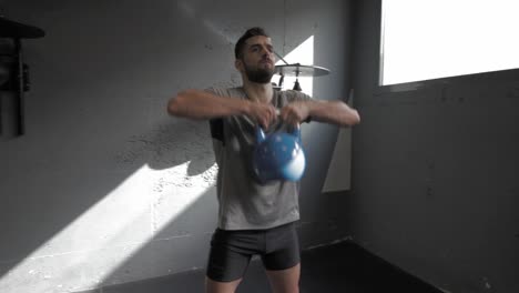 young athletic man doing exercise at the gym with kettlebell