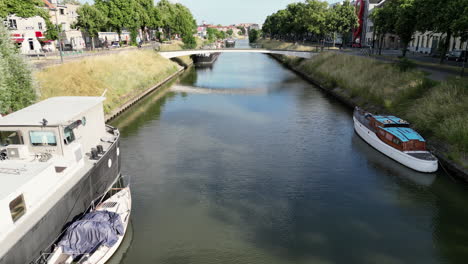 Low-Forward-Aerial-Between-Barge-Sitting-in-Canal-of-Ghent-with-Small-Bridge