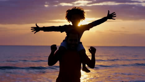 joyful father and child on a beach at sunset