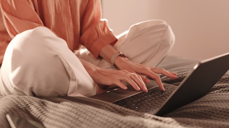 Person Using Computer Sitting on Bed