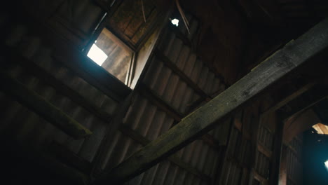 interior of abandoned zinc roofed triangle log cabin with wind moving interior items. low angle view of roof, pan right.
