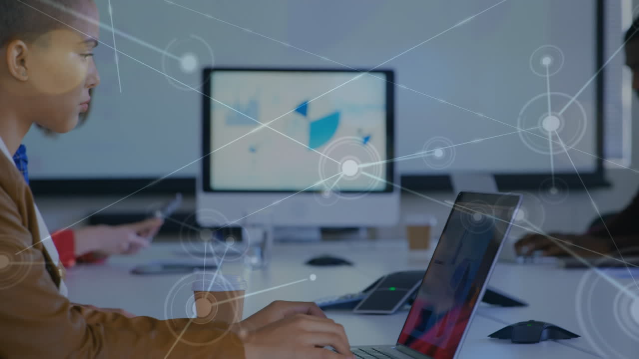 animación de puntos interconectados con líneas sobre colegas multirraciales trabajando en computadoras portátiles en la mesa