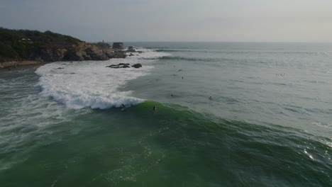 amplio disparo de dron de surfistas tratando de montar una gran ola frente a la costa de méxico