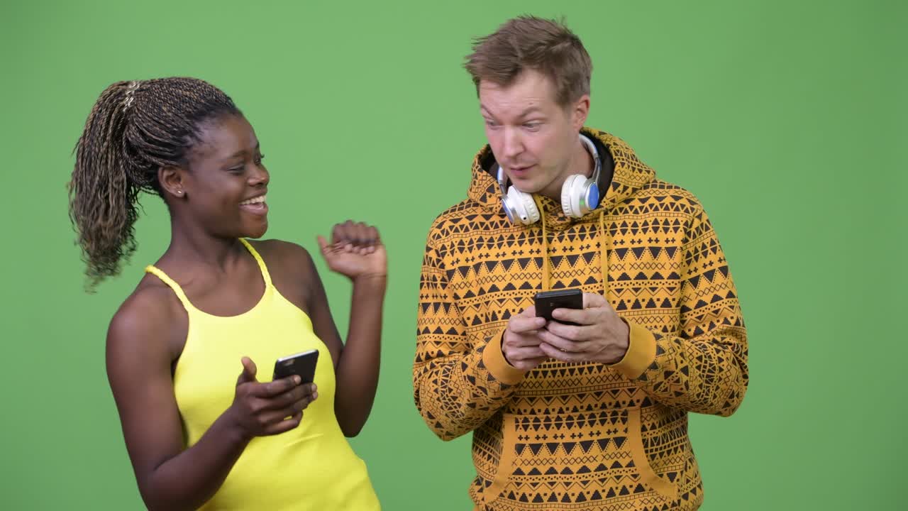 una joven pareja multiétnica usando el teléfono juntos.