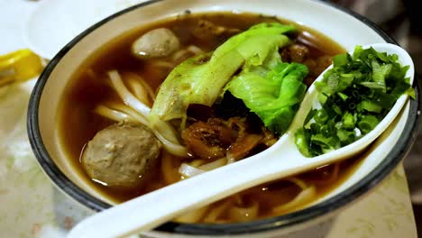 a bowl of beef noodle soup with toppings