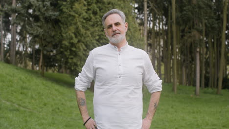 portrait of a gray haired man standing in the park and looking at the camera 4