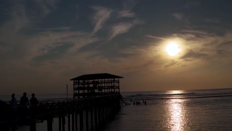 Toma-En-Cámara-Lenta-Del-Muelle-Al-Atardecer,-Las-Siluetas-De-Una-Marea-Baja-En-Filipinas