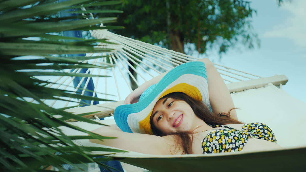 una bonita morena con un sombrero de ala ancha y en bikini disfruta relajándose en el balneario yace o
