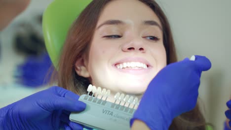 doctor examining patient teeth whiteness. close up dentist selecting color