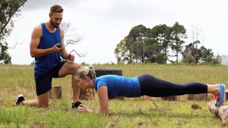 male trainer training woman during obstacle course