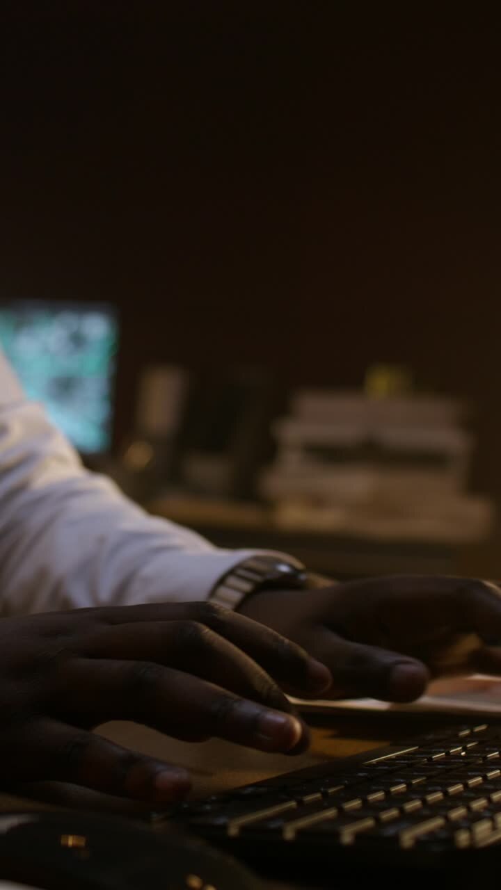 Person typing on a computer keyboard at night.