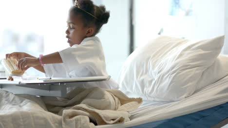 african american girl eating lunch in hospital bed, slow motion