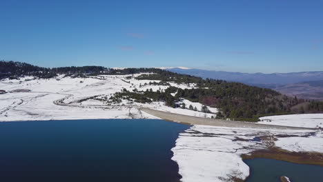 Aerial-view-of-snow-covered-mountain-range-and-lake-in-winter