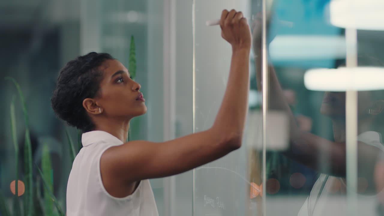 business woman writing on glass whiteboard female project manager brainstorming sales strategy using marketing data working late in office