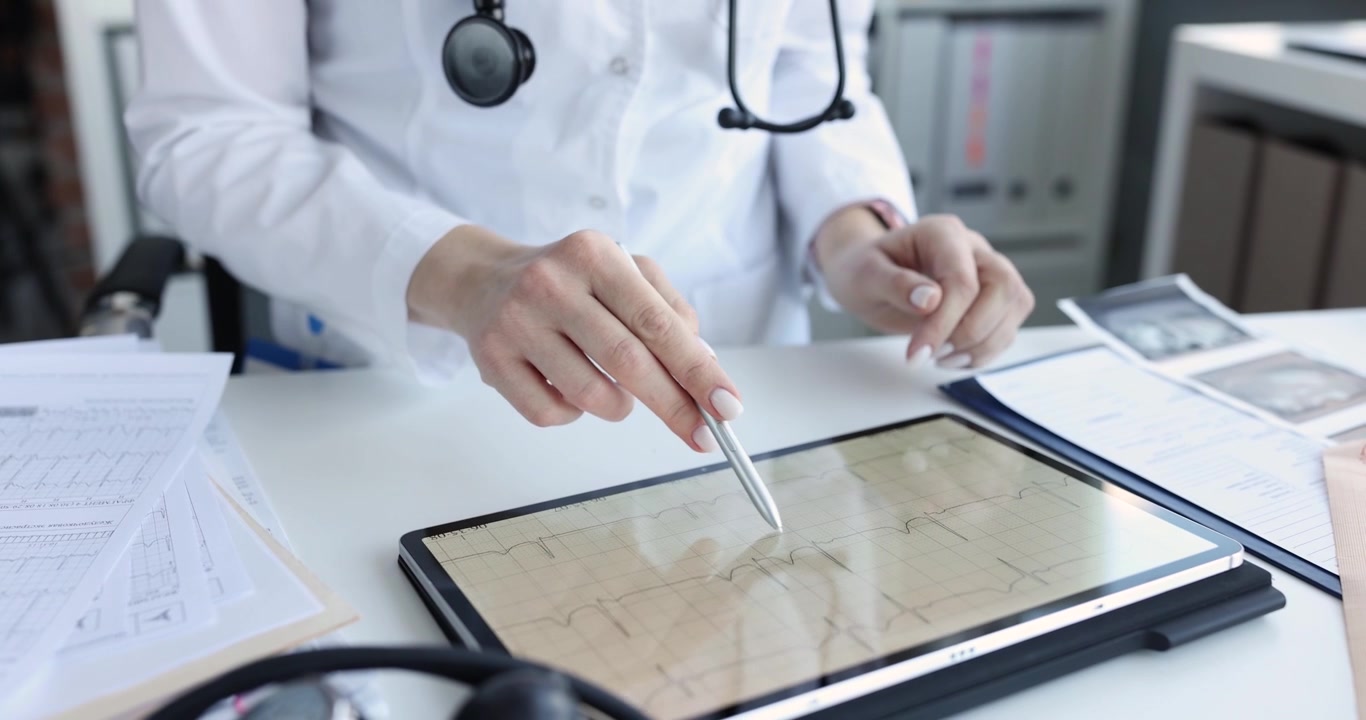 Mujer analiza el electrocardiograma de un paciente en una tableta digital