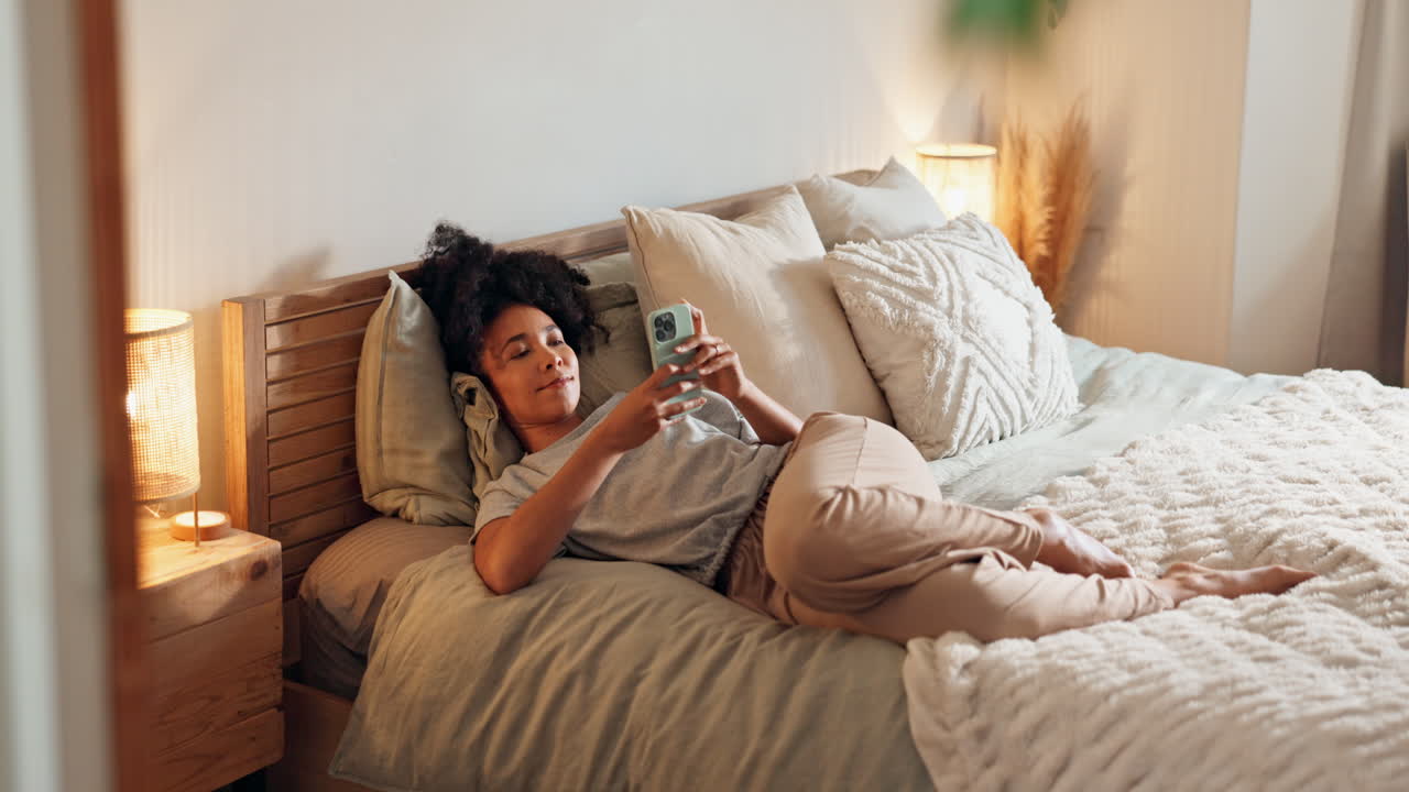 Donna che si rilassa a letto usando il telefono