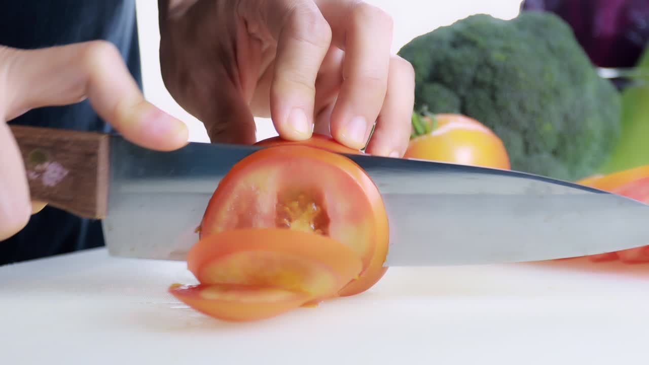 4k 여성 손으로 는 보드에 신선한 토마토를 잘라 여성 손은 기 보드에 칼로 원시 토마토을 원으로 잘라 건강한 음식 개념.