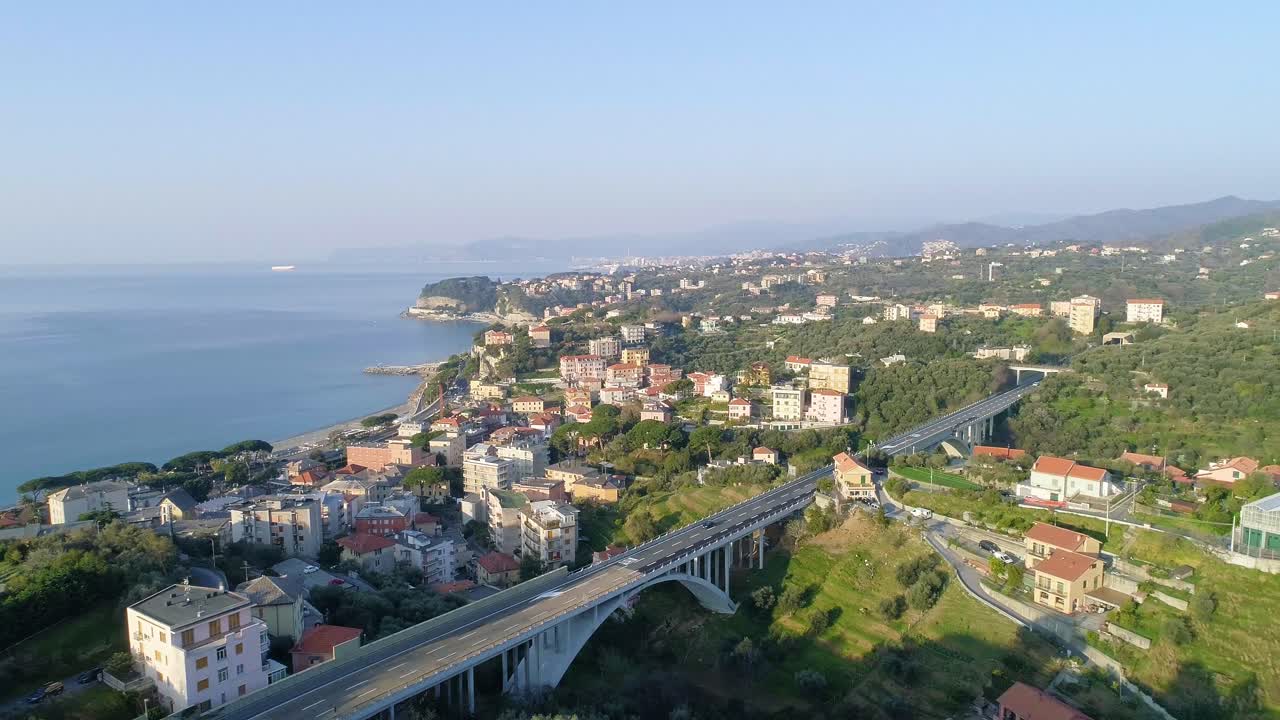 Inquadratura aerea panoramica di una città e un'autostrada sulla Costa Azzurra, sulla costa mediterranea, con un ponte e case che si affacciano sull'oceano.