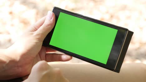 fondo al aire libre a principios de otoño con mujer sosteniendo pantalla verde teléfono 4k