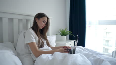 woman working on laptop in bed