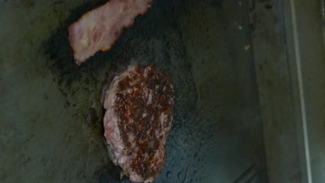 Vertical-Shot-Of-Meat-And-Bacon-For-Burger-On-A-Hot-Frying-Pan