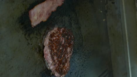 vertical shot of meat and bacon for burger on a hot frying pan