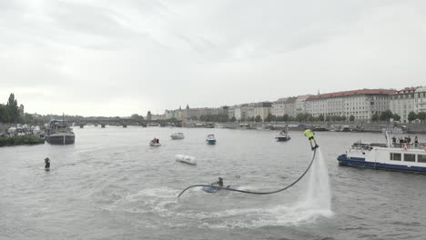 Guy-using-a-flyboard-above-Vltava-river,Prague,boats-and-water-scooters